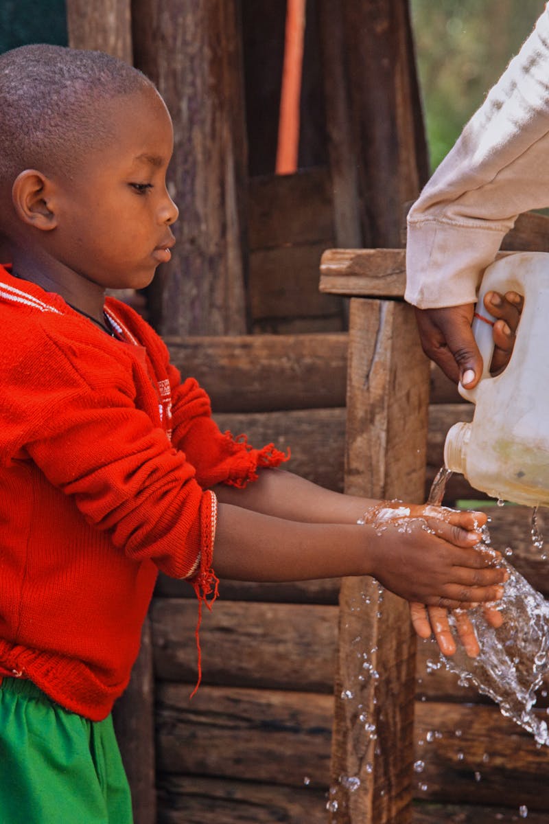 Young child washing hands in a rural area of Uganda, promoting hygiene awareness.